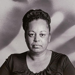 black and white portrait of woman, blurred hand pattern in background.