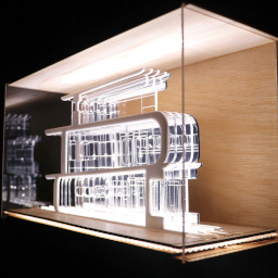 3D geometric acrylic model, curved features in a glass case with wooden back under LED lights.